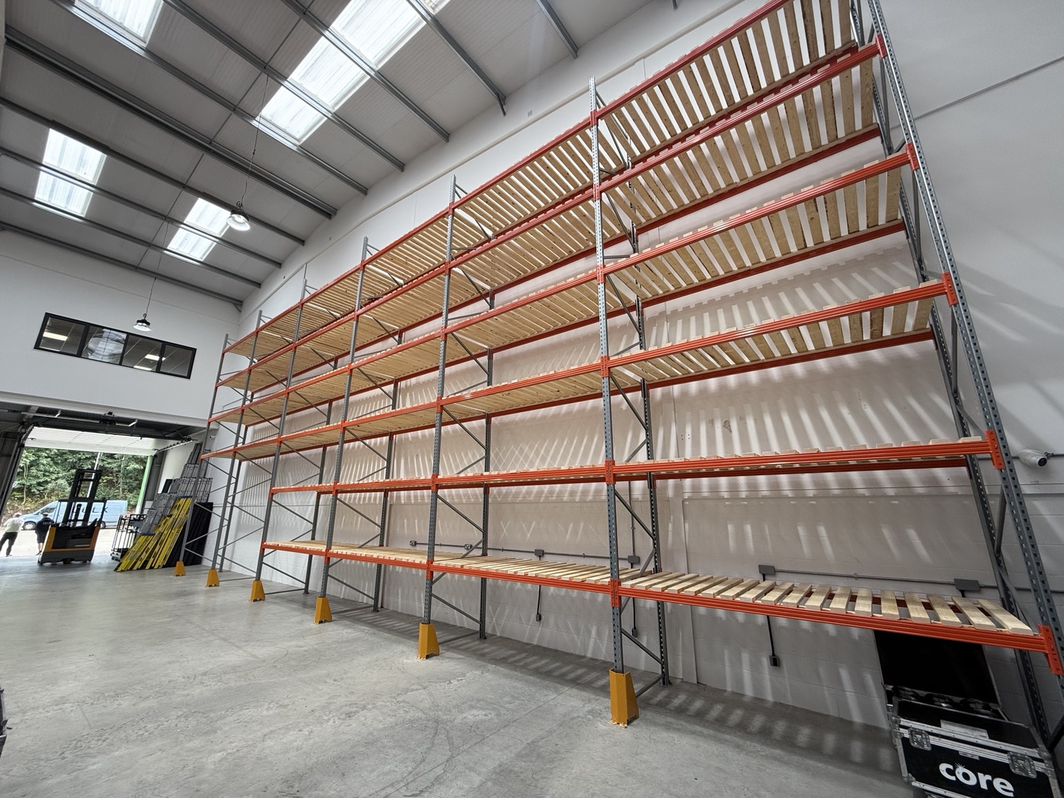 Completed pallet racking with orange beams, timber decking and yellow upright protectors